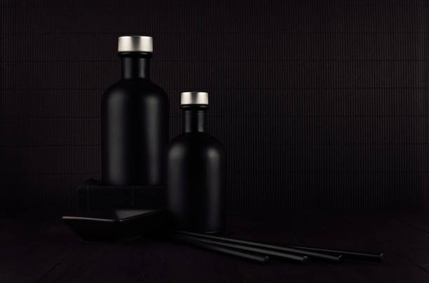 Dark black minimalist interior. Blank black cosmetics bottles on dark wood board with copy space. Noir elegant home decor for advertising, designers, branding identity, cover.