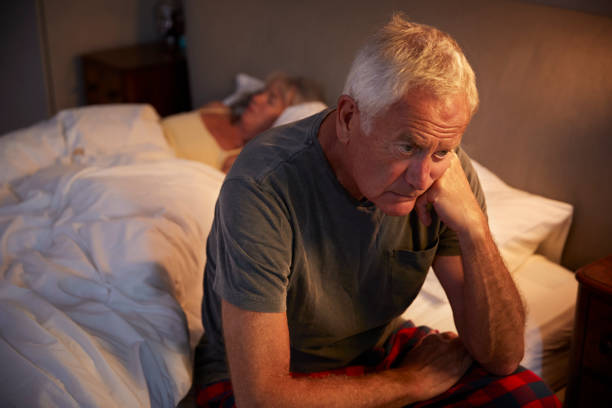 besorgt senior mann im bett in der nacht, die an schlaflosigkeit leiden - couple senior adult sadness emotional stress stock-fotos und bilder