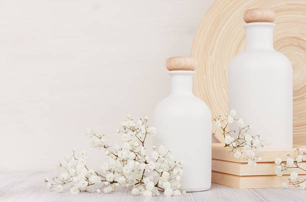 istock Blank white cosmetics bottles with small flowers on white wood board, copy space. Interior. Soft elegant home decor. 864371526