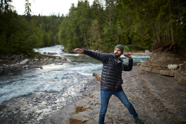 Young man skipping stones on mountain river