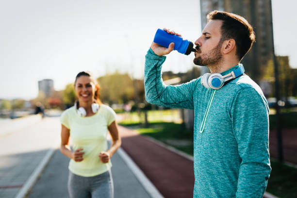 istock Young attractive couple running outside on sunny day 864381120