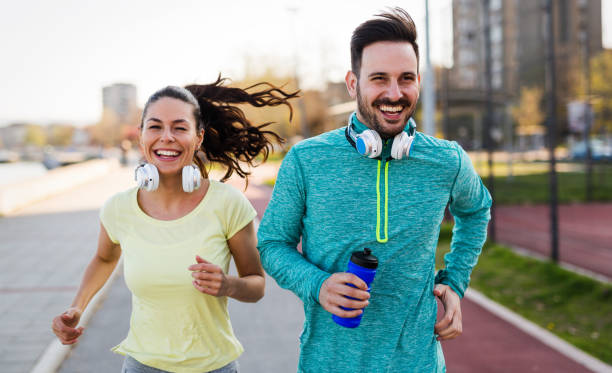 istock Young attractive couple running outside on sunny day 864383880