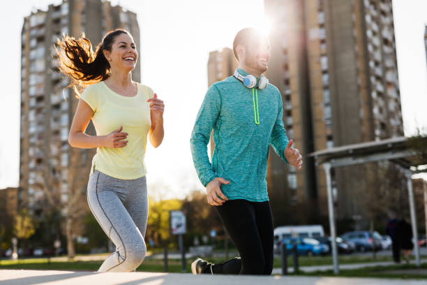 istock Young attractive couple running outside on sunny day 864384054