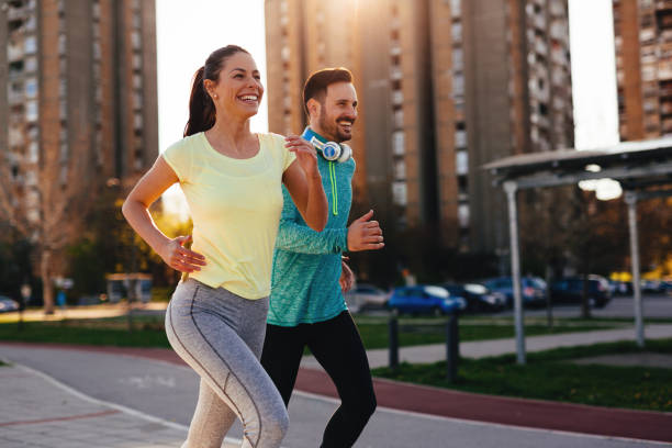 giovane coppia attraente che corre fuori nella giornata di sole - jogging foto e immagini stock