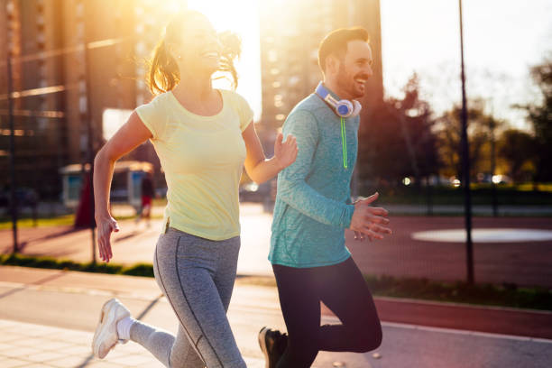 istock Young attractive couple running outside on sunny day 864384474