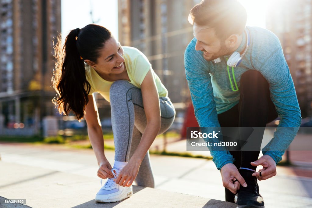 Runners tying running shoes and getting ready to run Runners tying their running shoes and getting ready for long run Exercising Stock Photo