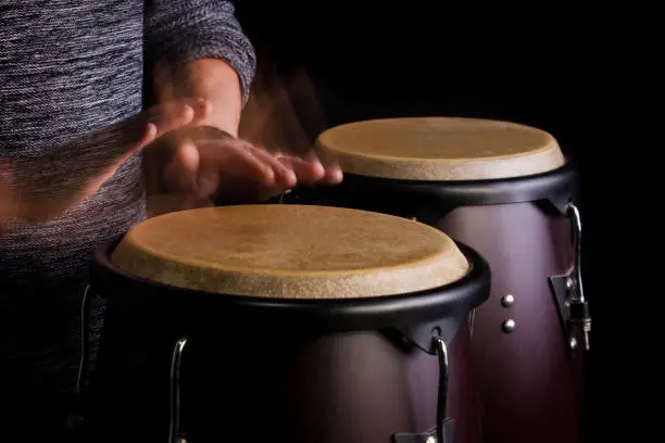 Motion Picture of a bongo Player. Black background.Picture is toned.