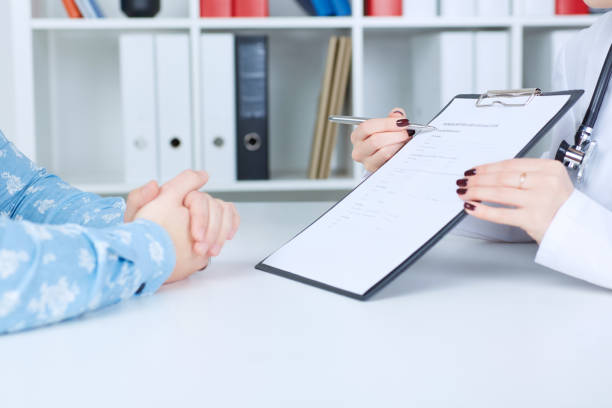 istock Female doctor holding application form while consulting patient. 864398048