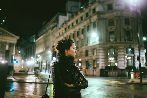 Young woman walking on the streets of London alone, wearing a black leather jacket and a backpack.