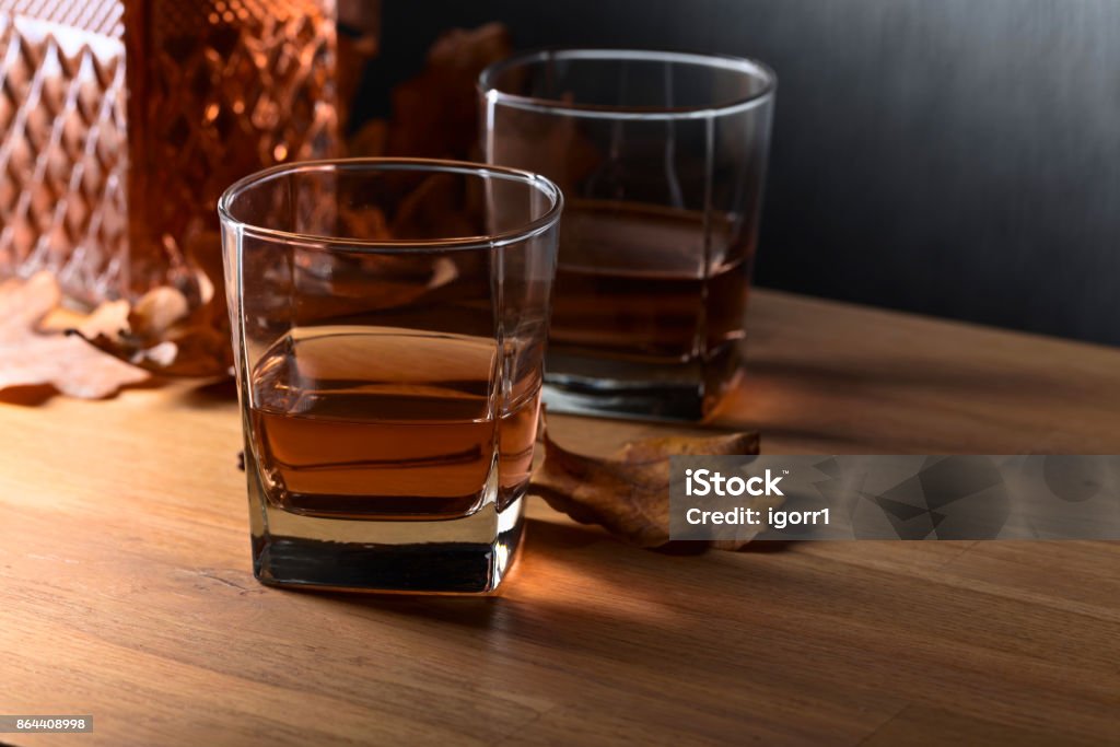 Whiskey on a old wooden table. Whiskey and dried up oak leaves on a old wooden table. Copy space . Alcohol - Drink Stock Photo