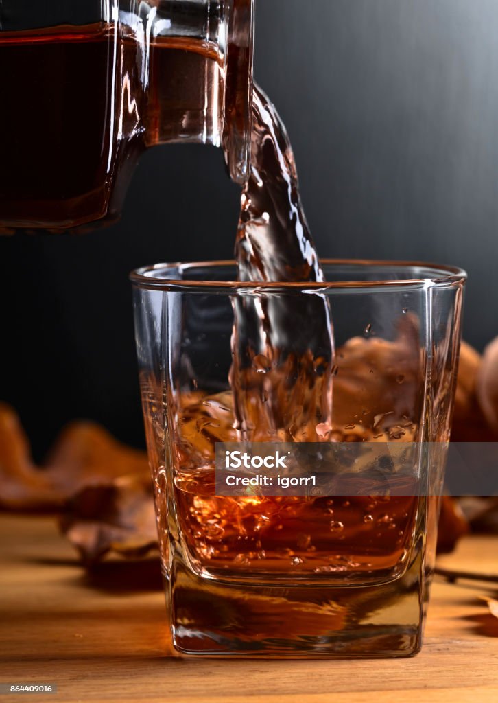 Whiskey on a old wooden table. Whiskey and dried up oak leaves on a old wooden table. Copy space . Alcohol - Drink Stock Photo