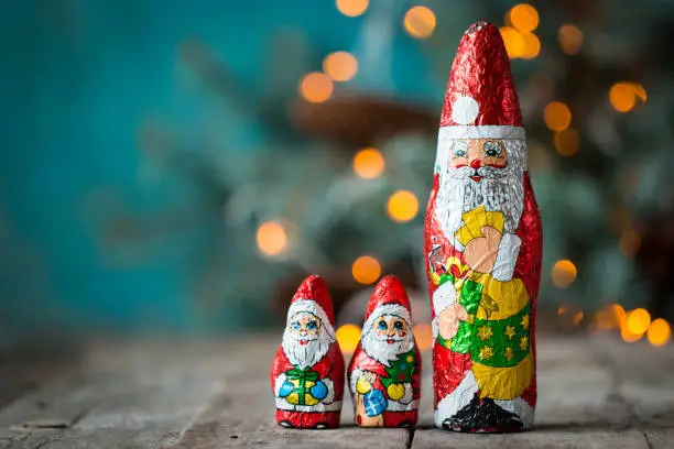 Photo of Chocolate Santa Claus with christmas lights on a old wooden background. christmas concept