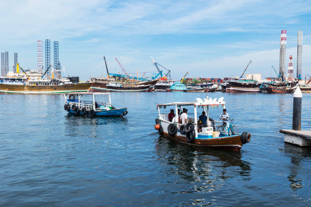 Water taxis with commuters, arriving to the Sharjah Corniche, with arabic style vessels and Port Khalid in the background
