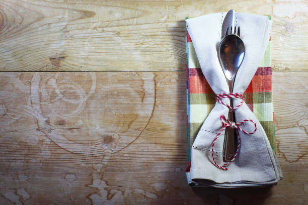 Rustic country picnic or holiday place setting with plaid and tan napkins tied with string, horizontal aspect