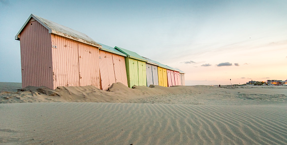 Multicolored bathing wooden huts lined up on the deserted beach of Berck-sur-Mer, France, in the early morning