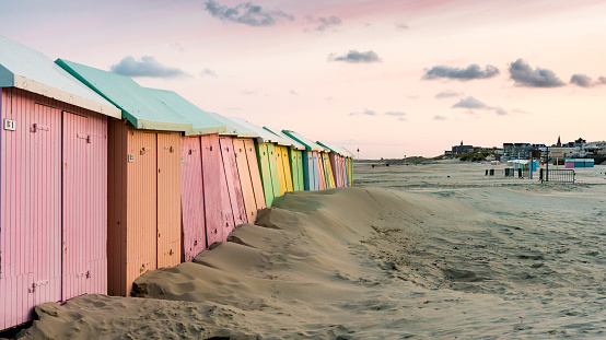 Multicolored bathing wooden huts lined up on the deserted beach of Berck-sur-Mer, France, in the early morning
