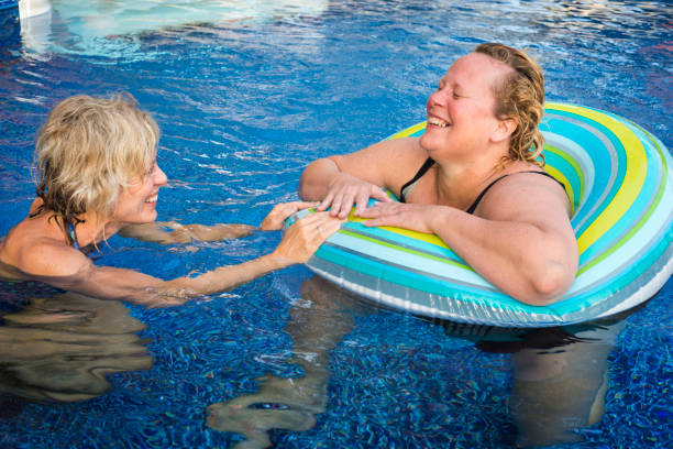 istock Two women laugh hysterically in a swimming pool 864425950