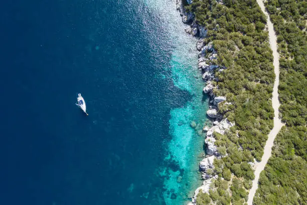 Photo of Beautiful beach, coast and bay with crystal clear sea water and a sailing yacht seen from above