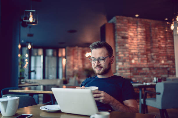 istock Young Smiling Hipster Freelancer Working in a Cafe Restaurant 864429786