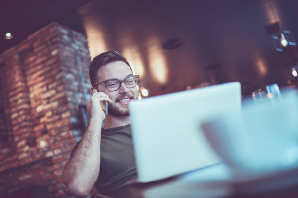istock Young Smiling Man Talking on Mobile Phone in Cafe Restaurant 864430104