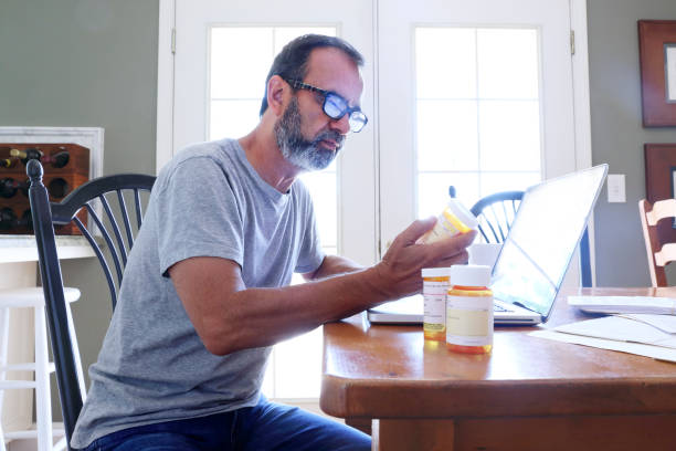 istock Hispanic Man Sitting At Dining Room Table Looking At His Prescription Medications 864430138