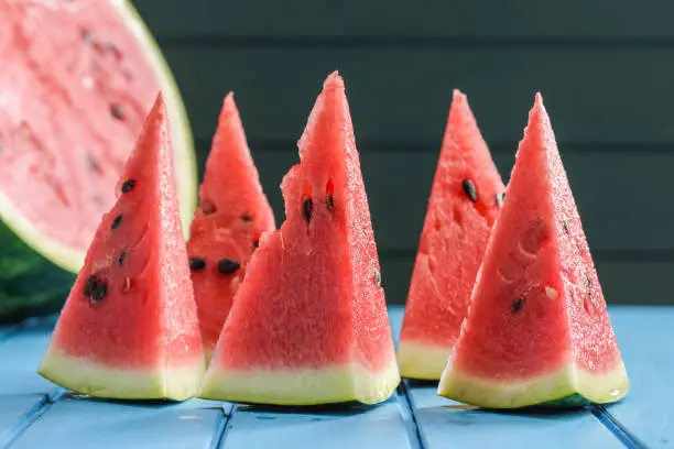 vegan snack. Fresh bright organic watermelon with seeds cut into triangles on blue background closeup