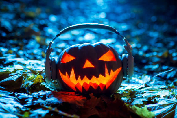 cabeza de calabaza de halloween con música de halloween de auriculares jack linterna sobre fondo oscuro - wood texture audio fotografías e imágenes de stock