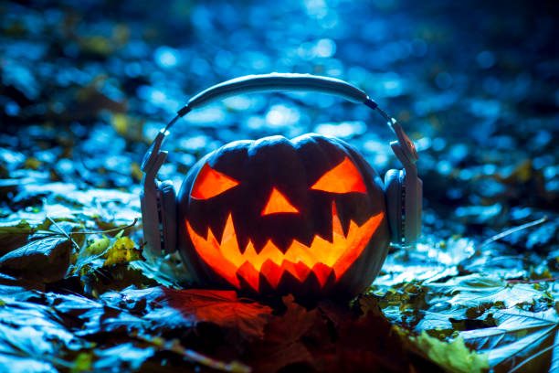 halloween pumpkin head with headphones halloween music, jack lantern on dark background stock photo