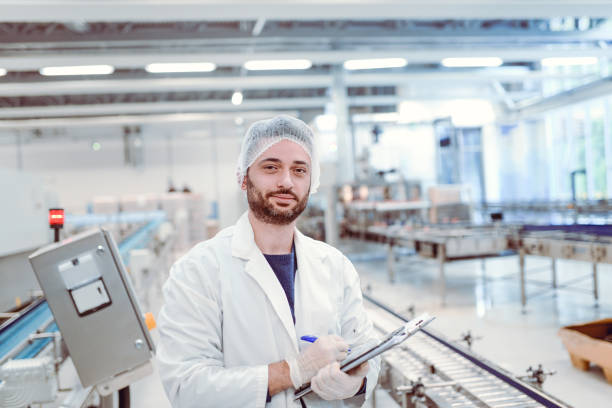 istock Young Cheerful Scientist With Clipboard Posing in Factory 864433138