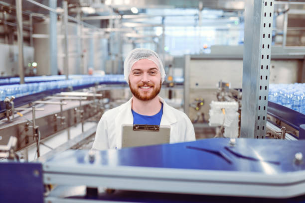 istock Young Handsome Smiling Scientist With Clipboard Posing in Factory 864433970
