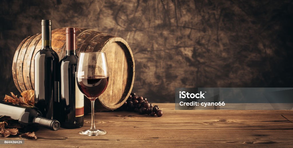 Traditional winemaking and wine tasting Wine glass, wooden barrel and collection of excellent red wine bottles in the cellar: traditional winemaking and wine tasting concept Wine Stock Photo