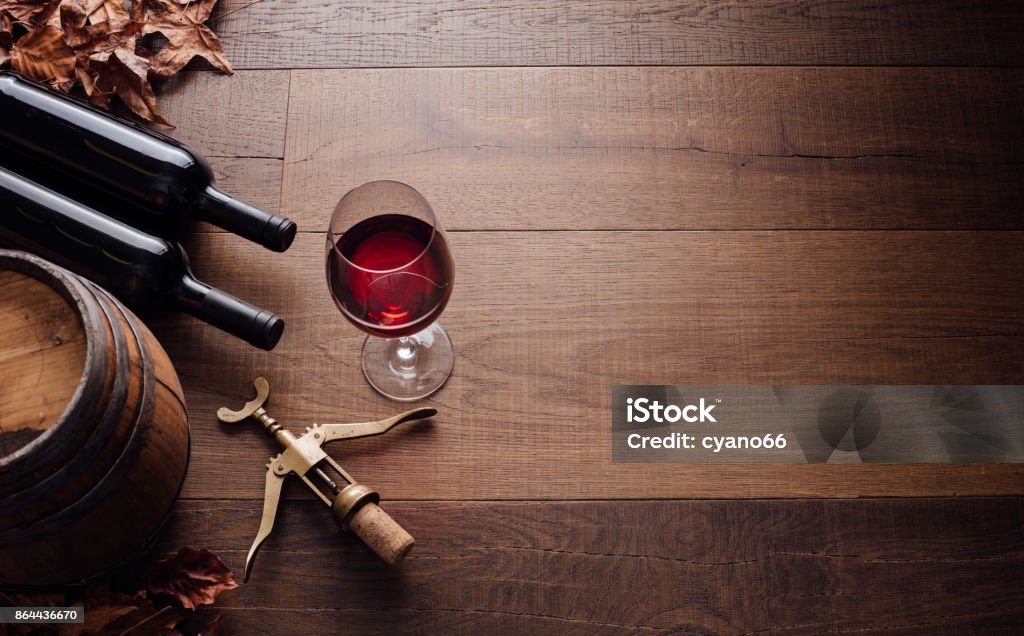 Tasting excellent red wine Excellent red wine bottles, wineglass, barrel and corkscrew on a rustic wooden table: traditional winemaking and wine tasting concept Wine Stock Photo