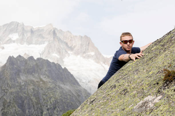 istock A climber makes climbing exercises on a big rock. In the background, the breathtaking mountain scenery of the Alps 864438486