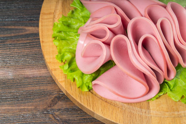 sliced sausages with salad leaves on the wood background - bologna imagens e fotografias de stock