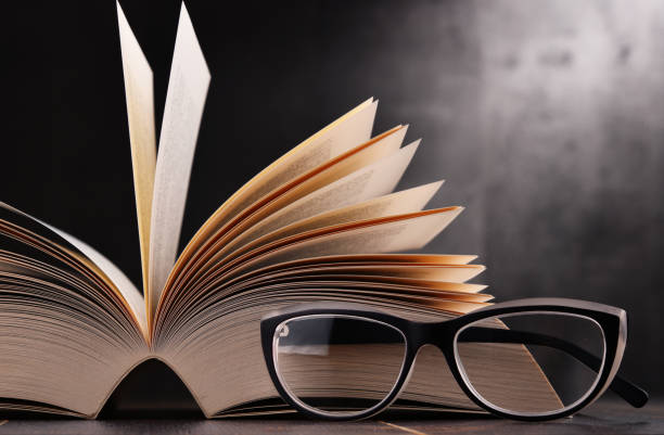 istock Composition with open book and glasses on the table 864441614