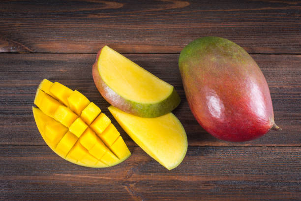 istock Tropical fruit mango on a wooden background, whole or sliced. 864442582