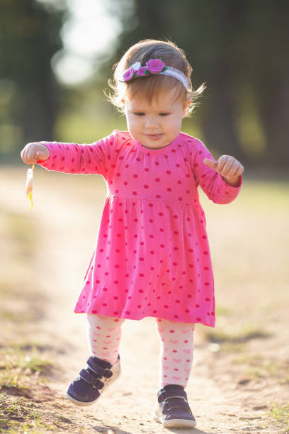 istock Baby girl outdoors taking her first steps close up shot 864445618