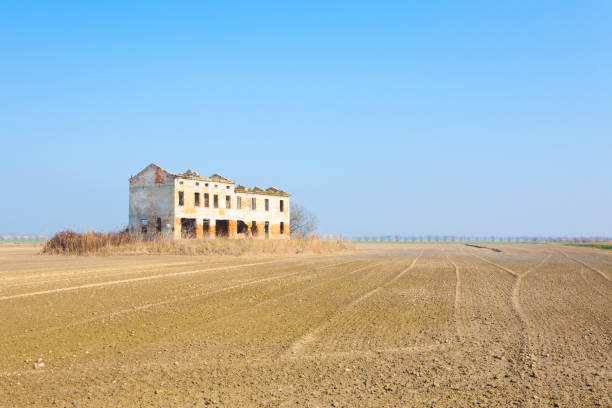 Rural Italian landscape from Po river lagoon.Plowed fields with perspective lines. Abandoned warehouse