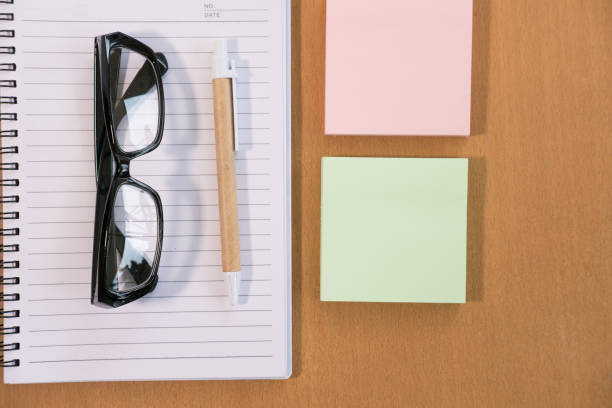 istock sticky note, ballpoint pen, empty notebook, eyeglasses on office desk. business, education concept. Top view with copy space. selective focus. 864453630