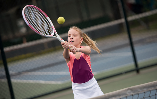 Beautiful girl playing tennis and hitting a ball with the racket - sports concepts