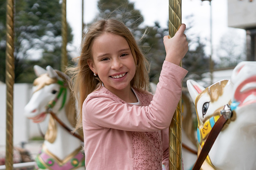 Portrait of a beautiful girl riding on the carrousel at a traveling carnival - lifestyle concept