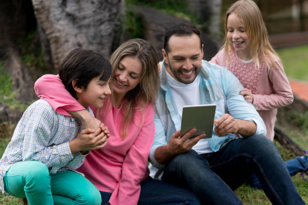istock Happy family social networking outdoors on a digital tablet 864453832