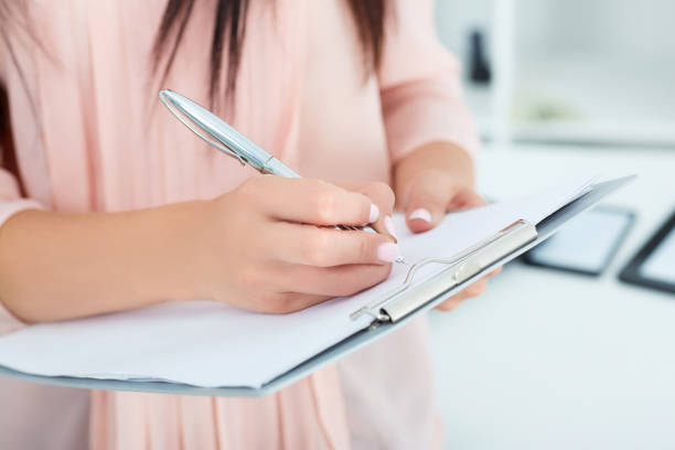 istock Young woman writing on black clipboard 864457162