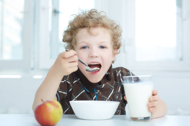 Boy eating cereal while having breakfast  in the kitchen. Boy eating cereal while having breakfast  in the kitchen. boys bowl haircut stock pictures, royalty-free photos & images
