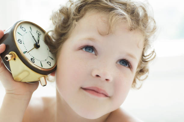 istock Pensive little boy listen an antique clock. 864458406