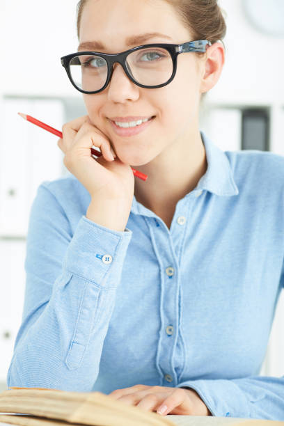 istock Female student at workplace with book holding red pencil studying. Education, self development and perfection concept 864458562