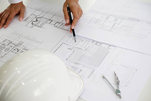 istock Architects engineer discussing at the table with blueprint - Closeup on hands and project print. 864458722