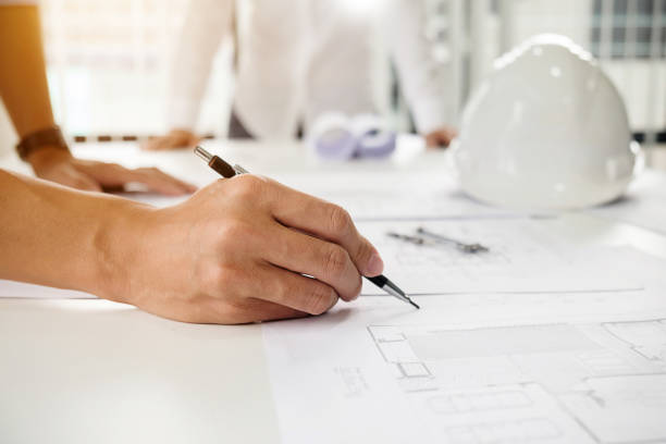 istock Architects engineer discussing at the table with blueprint - Closeup on hands and project print. 864458738