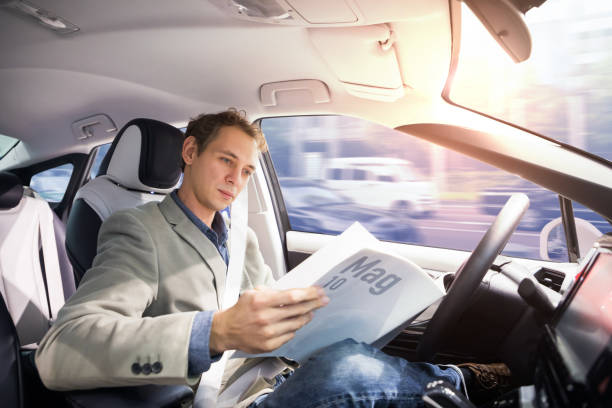 controlador caucásico leer revista en coche autónoma. mismo vehículo. coche sin conductor. - vehículos sin conductor fotografías e imágenes de stock