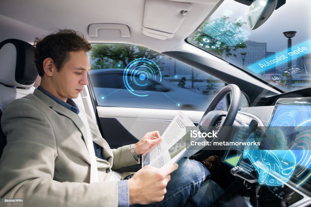 Caucasian driver reading magazine in autonomous car. Self driving vehicle. Driverless Transport Stock Photo